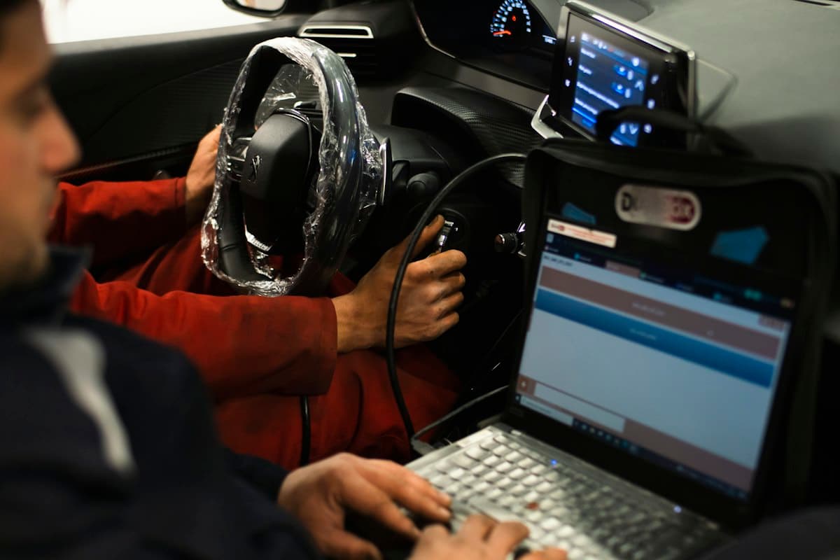فني يوصل جهاز برمجة بمنفذ OBD في سيارة حديثة داخل ورشة
